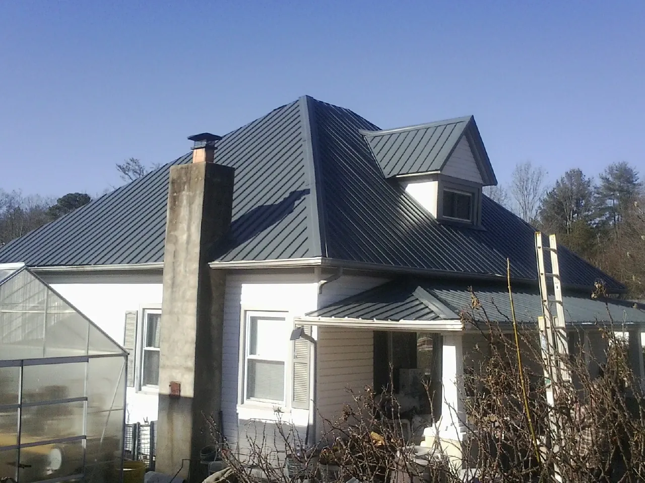 Dark blue standing seam metal roof on a white farmhouse with dormer — Slate & Tile Roof Repair by Roofing Brothers in Lisbon